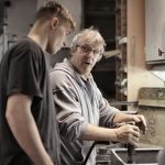 Experienced mentor teaching a manufacturing apprentice