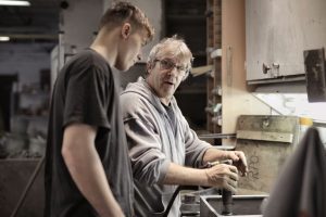 Experienced mentor teaching a manufacturing apprentice
