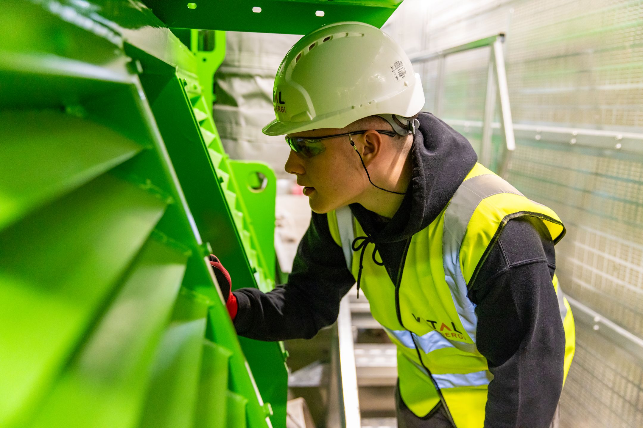 Worker in safety vest inspecting industrial machinery