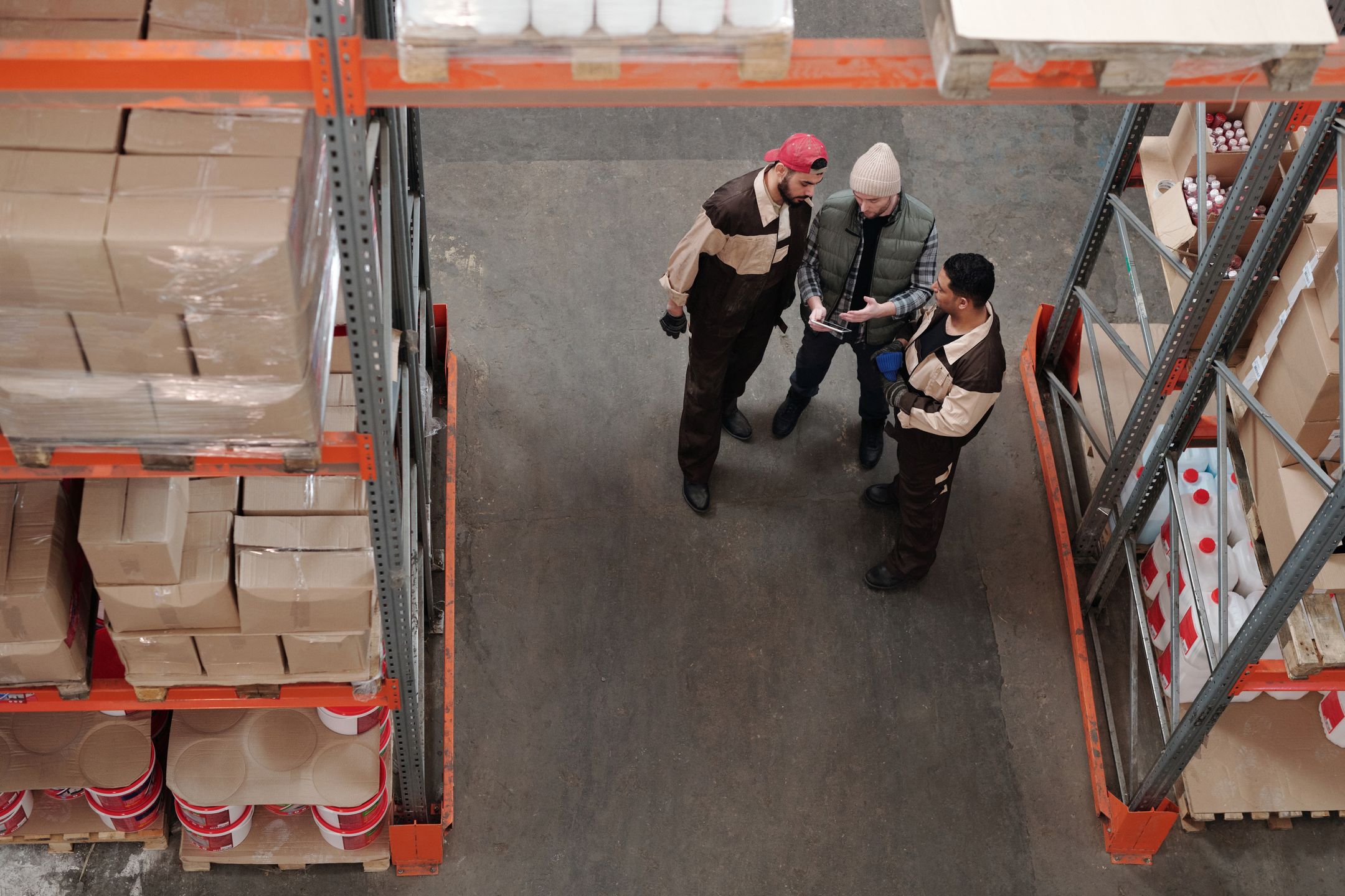 Workers discussing a process near warehouse inventory shelving
