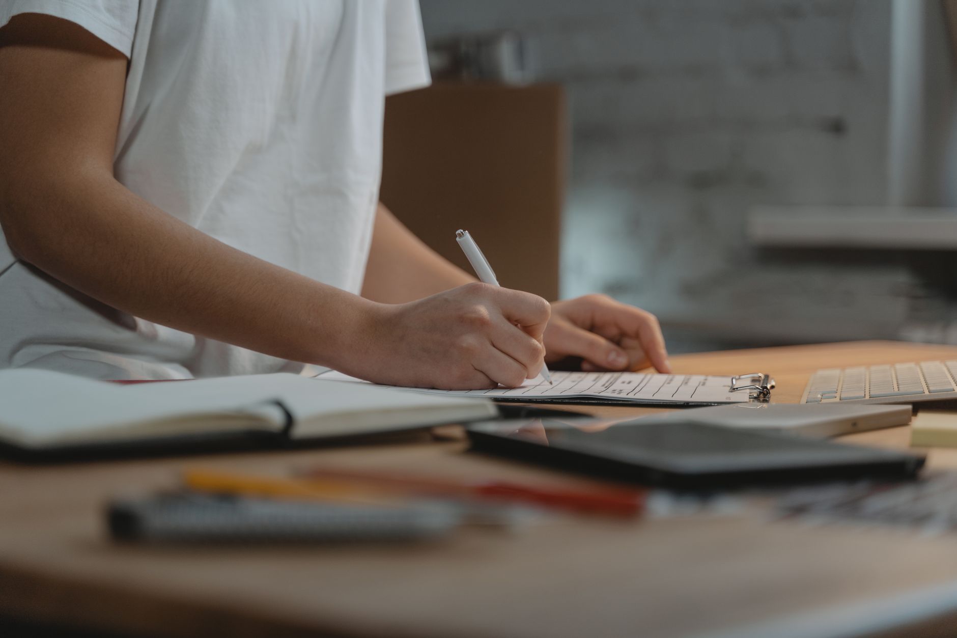 Close-up of a hand writing on a clipboard checklist at a desk