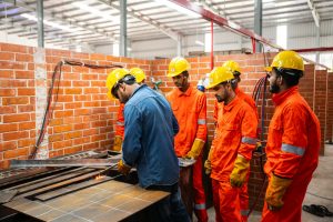 Manufacturing supervisors in hard hats and high-visibility vests talking on a workshop floor
