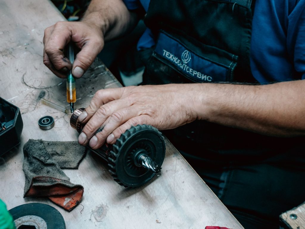 Technician using a grease gun on industrial equipment