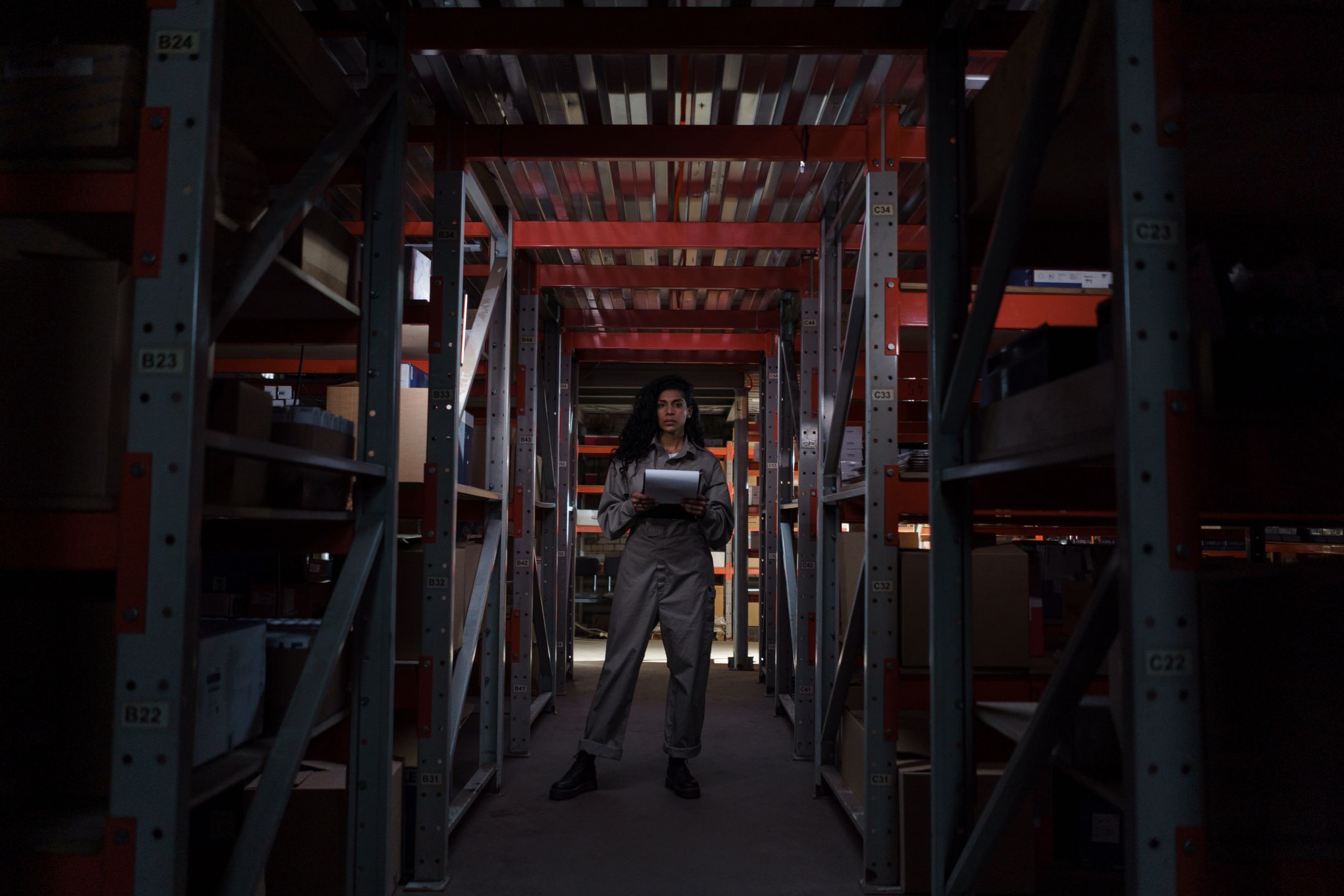 Warehouse worker holding a clipboard among industrial shelves