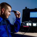Technician performing ultrasonic nondestructive testing on a metal part