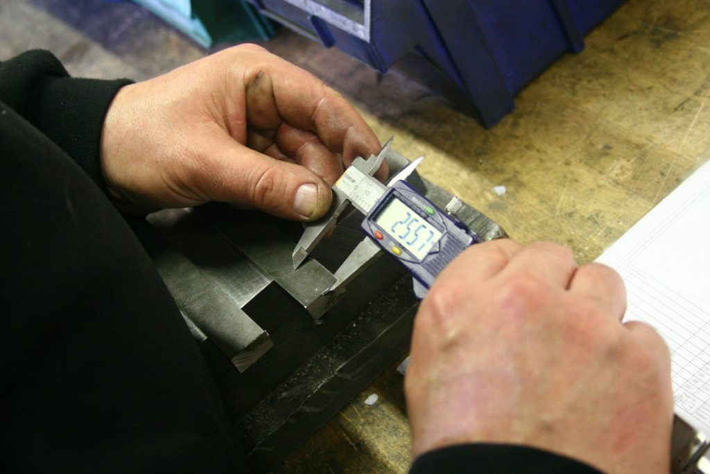 Technician using digital calipers to inspect a machined part