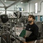 Reliability engineer inspecting industrial piping and equipment on the plant floor