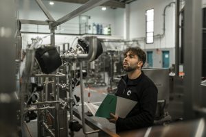 Reliability engineer inspecting industrial piping and equipment on the plant floor