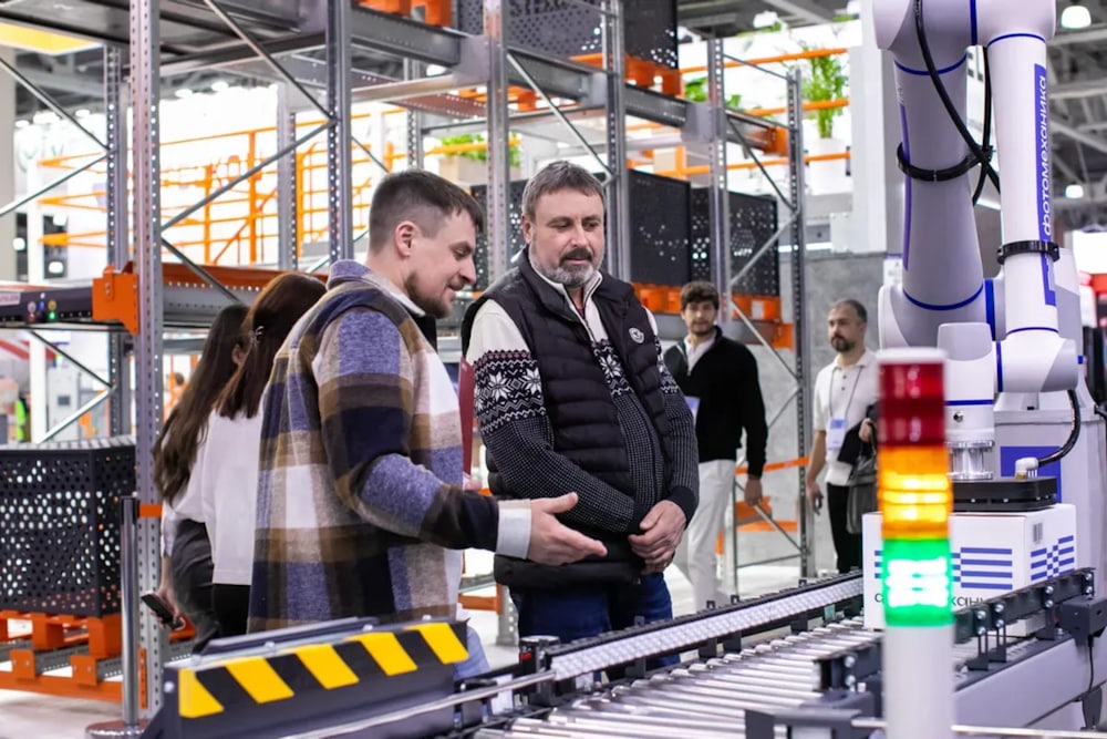 People observing a robotic automation system on a production line