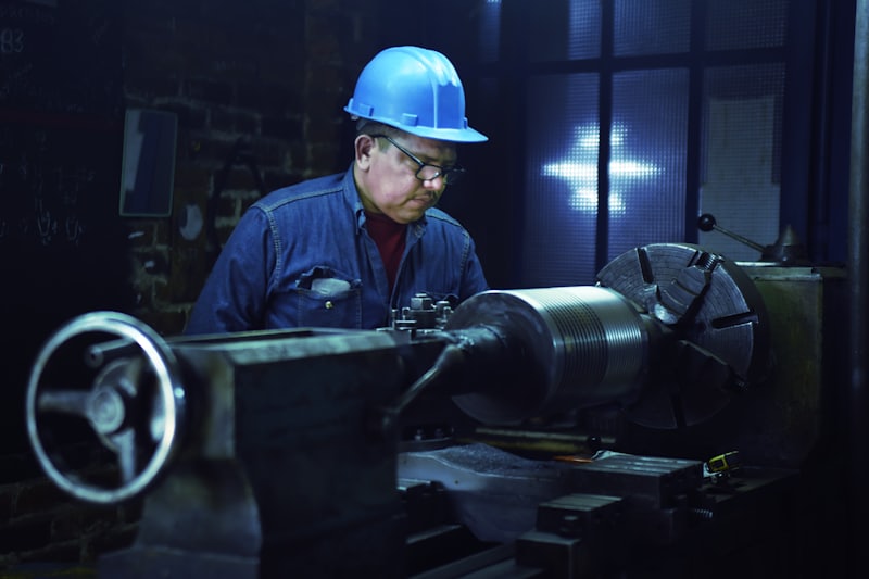 Machine operator in a hard hat working at a lathe