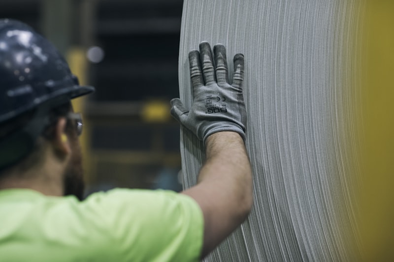 Worker in a hard hat and protective gloves handling material inside a plant