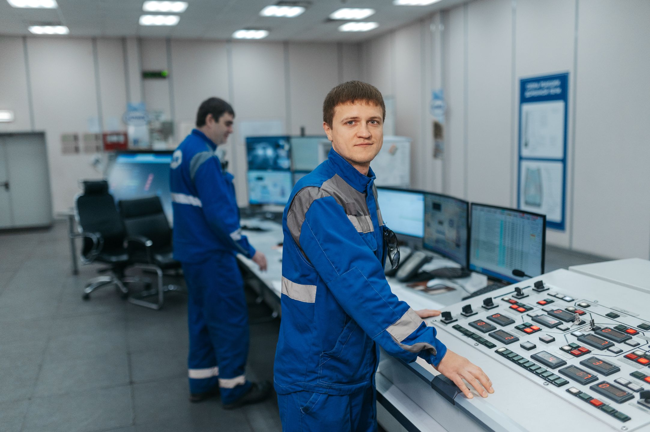 Two technicians operating machinery in a modern control room