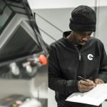 Manufacturing technician completing a structured check sheet beside an industrial machine
