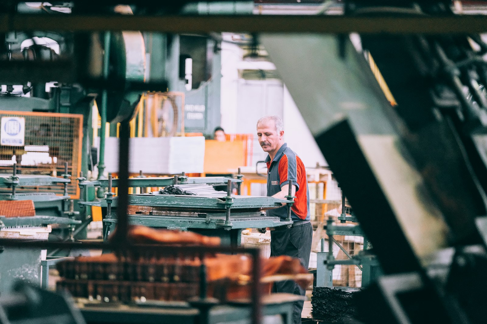 Experienced worker reviewing documents on the production floor with a colleague nearby