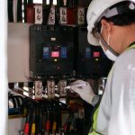 Technician using an infrared camera to scan an electrical panel